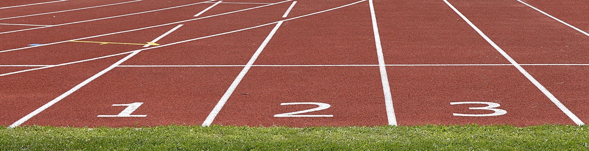 Sporteinrichtung Eine rote Kunststoffbahn umgeben von grünem Rasen