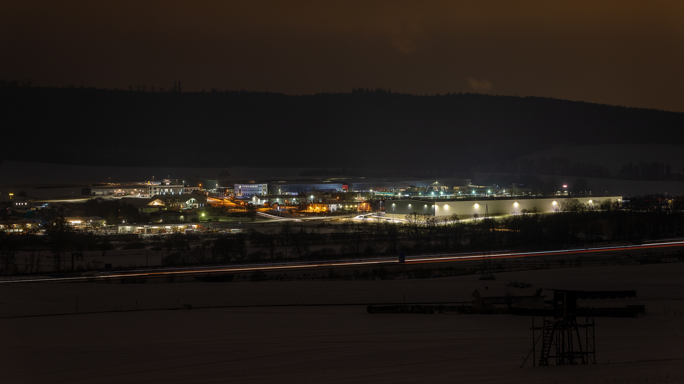 Fotografieren in Neuhof - Winterzeit Beleuchtete Unternehmens-Gebäude, liegend im Gewerbegebiet bei Dunkelheit und umgeben von Bäumen.