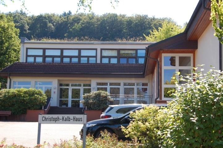 Ein Gebäude, Dorfgemeinschaftshaus. Im Vordergrund ist der Straßenname "Christoph-Kalb-Haus" auf einem Schild abgebildet.