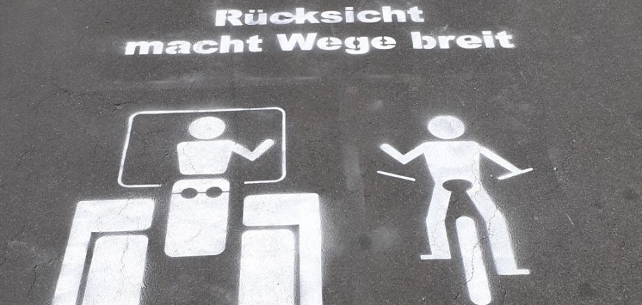 Zu sehen ist ein Piktogramm auf einem asphaltierten Weg. Enthalten ist ein Traktor, ein Radfahrer und der Schriftzug "Rücksicht macht Wege breit. Danke! Ihre Landwirte".